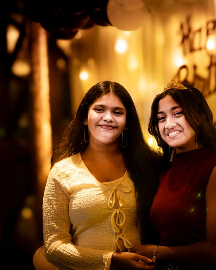 Aniversariante de tiara sorri ao lado de uma amiga