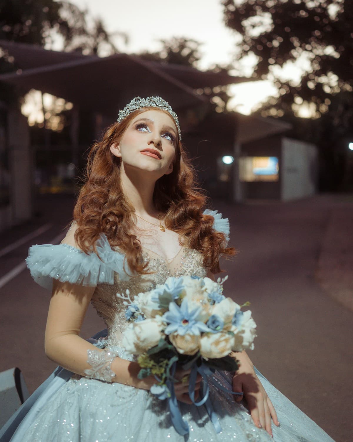 Debutante de vestido azul-claro e tiara segura o buquê